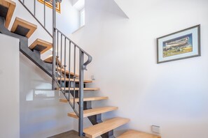 Eine moderne Treppe mit Holzdielen und Metallgeländern, die zu einer Zwischenebene mit einem gerahmten Kunstwerk führt.
