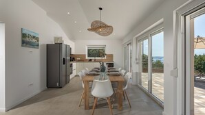 A modern kitchen with a dining area, large windows, and a view of the outdoors. - Holiday Home Elora Seaview Private Pool And Garden, Kostrena, Croatia (Kostrena)