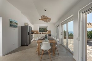 Eine moderne Küche mit Essbereich, großen Fenstern und Blick ins Freie.