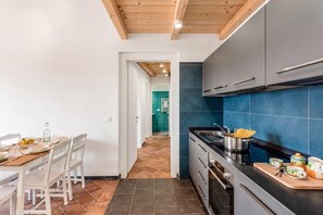 Une cuisine moderne avec un coin repas, caractérisée par un plafond en bois, un pare-feu en carreaux bleus et une table à manger dressée avec des assiettes et des verres.