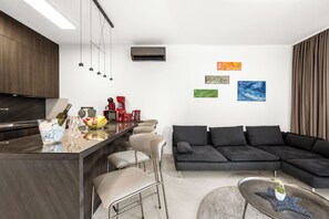 A modern kitchen with a bar area, a black sectional sofa, and artwork on the walls. - Pure Bliss Villa With Jacuzzi, Tisno, Croatia (Tisno)
