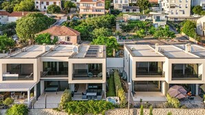 Um edifício residencial moderno com terraço no telhado, piscina e jardim bem cuidado.