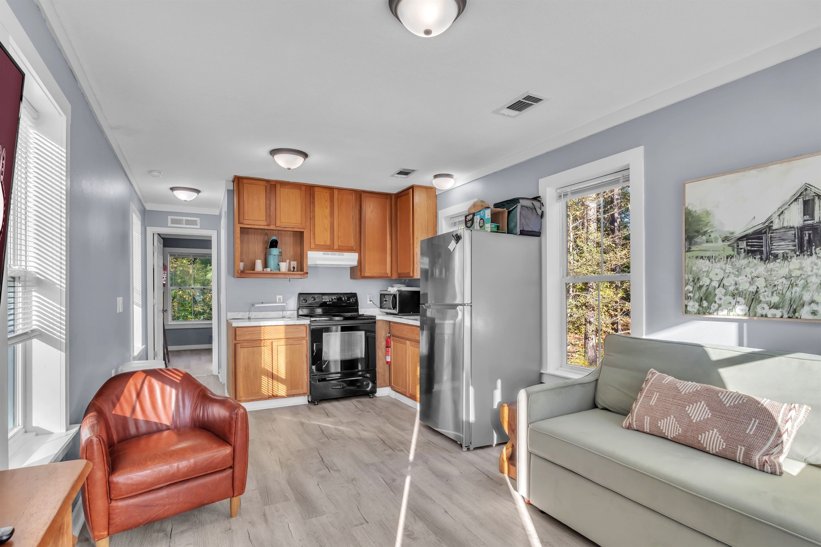 A modern kitchen with wooden cabinets, a stainless steel refrigerator, and a built-in oven.