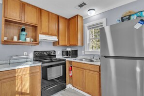 A modern kitchen with wooden cabinets, a stainless steel refrigerator, a microwave, and a stove.