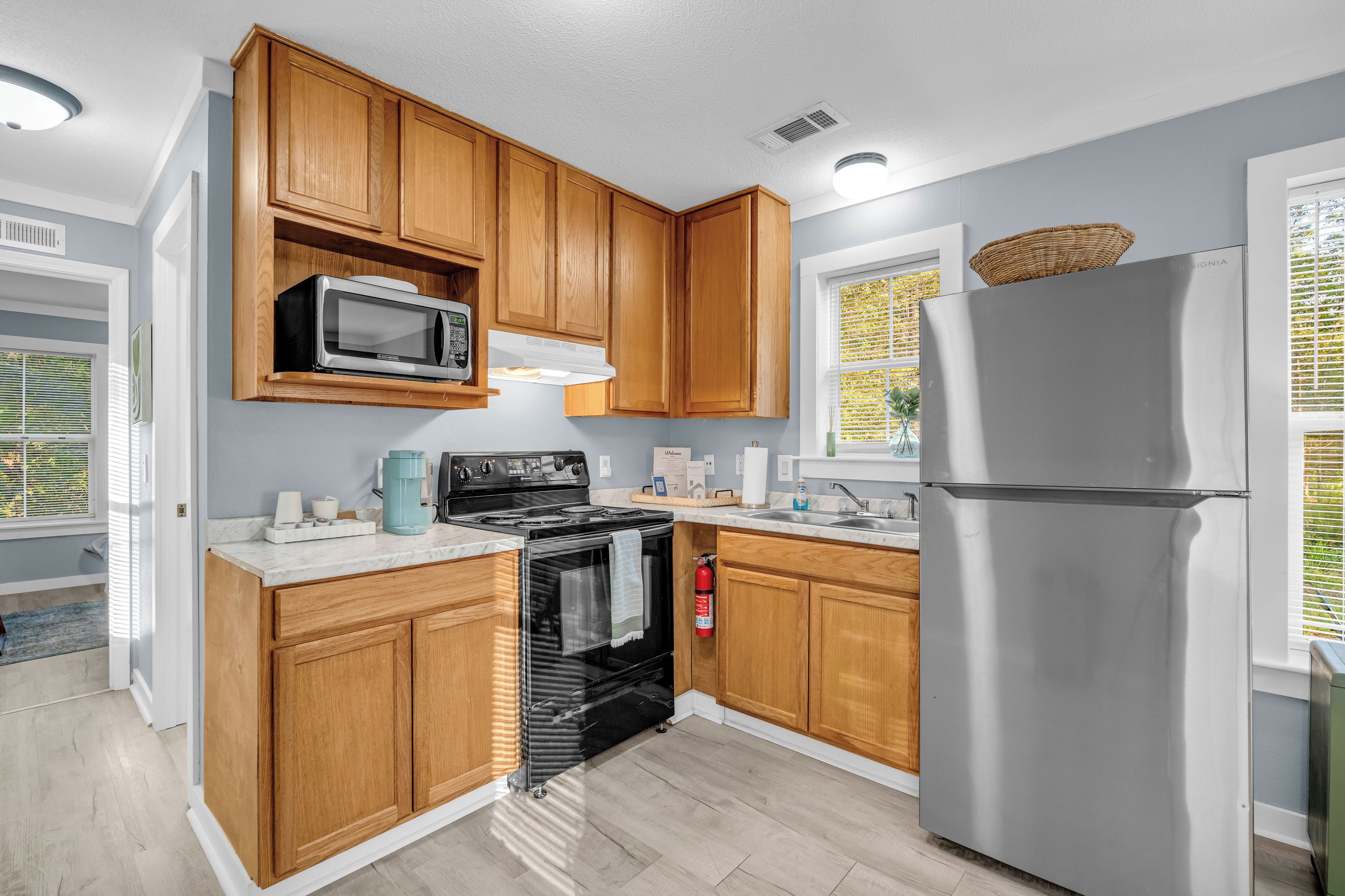 A modern kitchen with wooden cabinets, a stainless steel refrigerator, a microwave, and a stove.