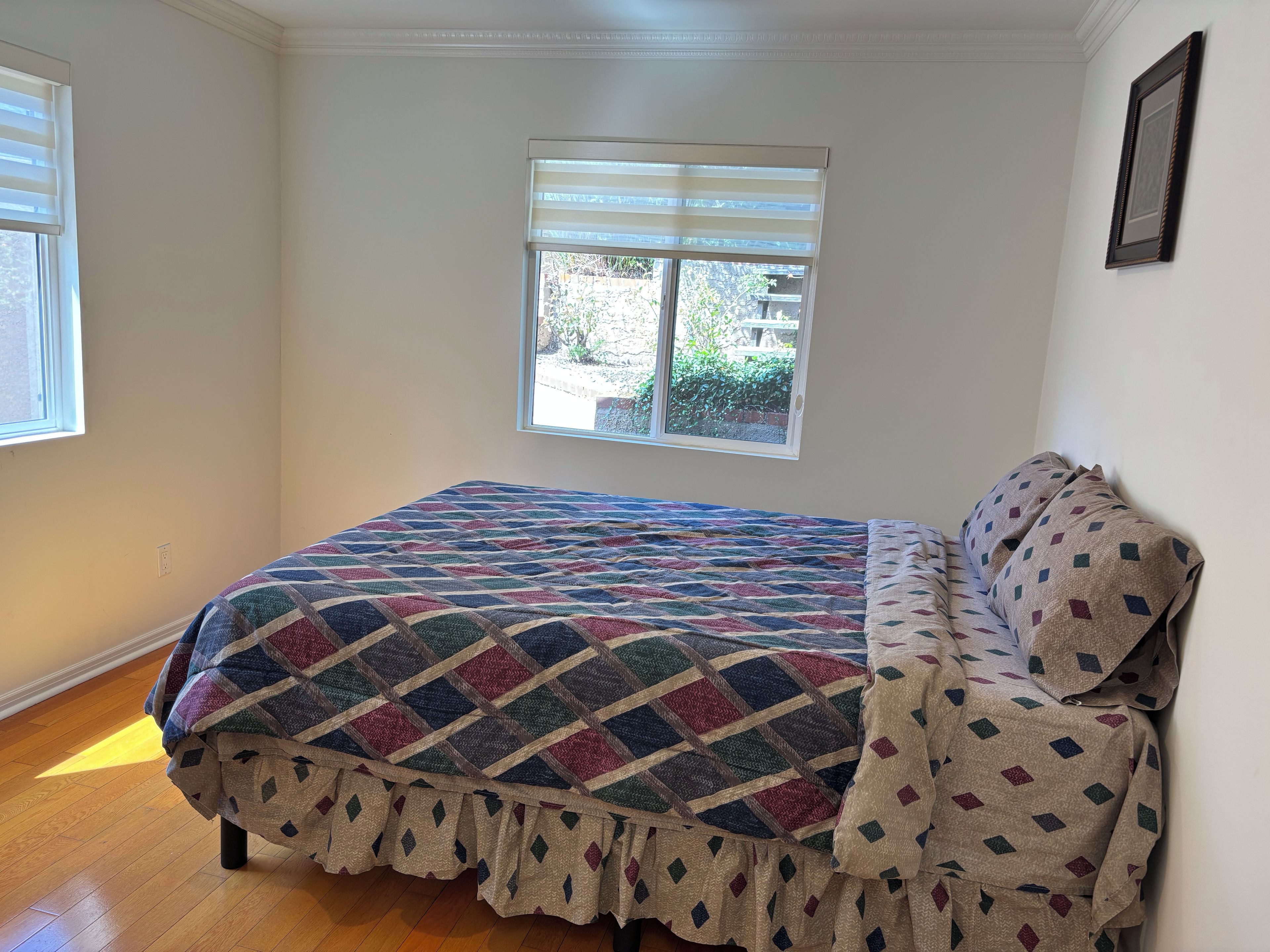 A bedroom with a bed, a window, and a door.