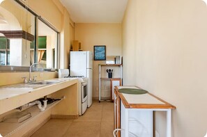 A compact kitchen with a sink, stove, and refrigerator. - Casa Blanca: 4-unit building with rooftop lounge, minutes from 5 Avenida (Playa del Carmen)