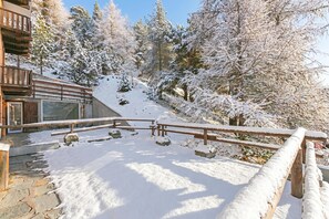 Eine Holterrasse mit verschneiter Landschaft, ein Gebäude mit großen Fenstern und einem klaren Himmel.