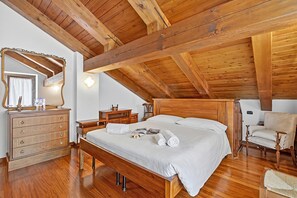 A bedroom with a wooden ceiling, a bed with white linens, a wooden dresser, a chair, and a mirror. - Alpine Loft Sommeiller, Bardonecchia, Italy (Bardonecchia)
