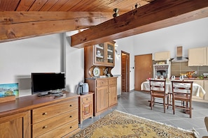A kitchen with wooden cabinets, a dining table set for two, and a television on a wooden cabinet. - Alpine Loft Sommeiller, Bardonecchia, Italy (Bardonecchia)