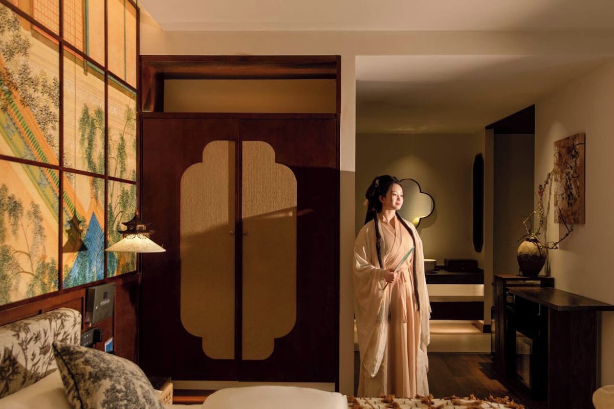 A traditional interior with a sliding door, a sofa, a lamp, and a decorative vase.