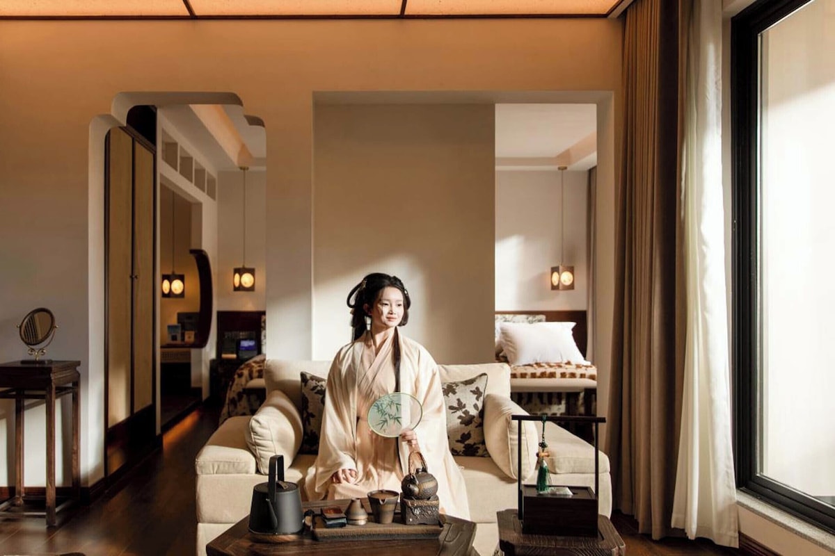 A traditional Japanese-style room with tatami flooring, a low table with tea set, and a large mirror.