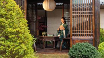 A traditional Chinese-style building with a wooden door and window grille, a table with teaware, and a hanging lantern.