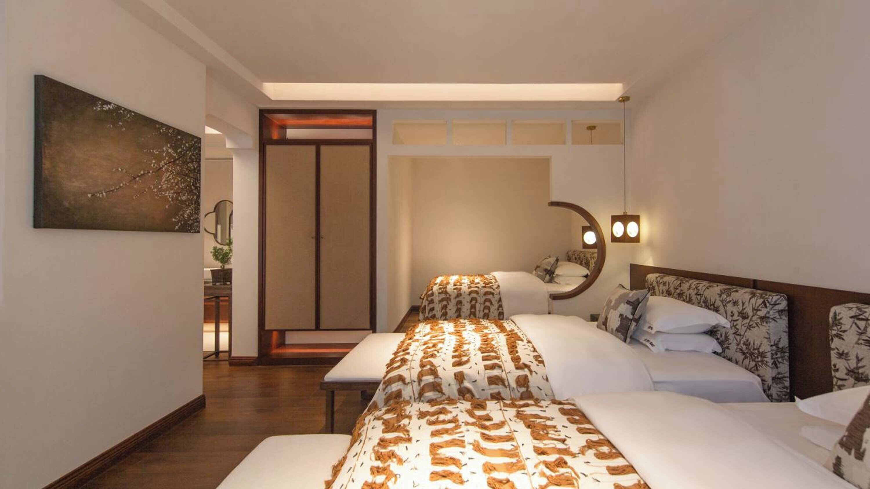 A hotel room with a bed, bedside tables, a mirror, and a wall-mounted light fixture.