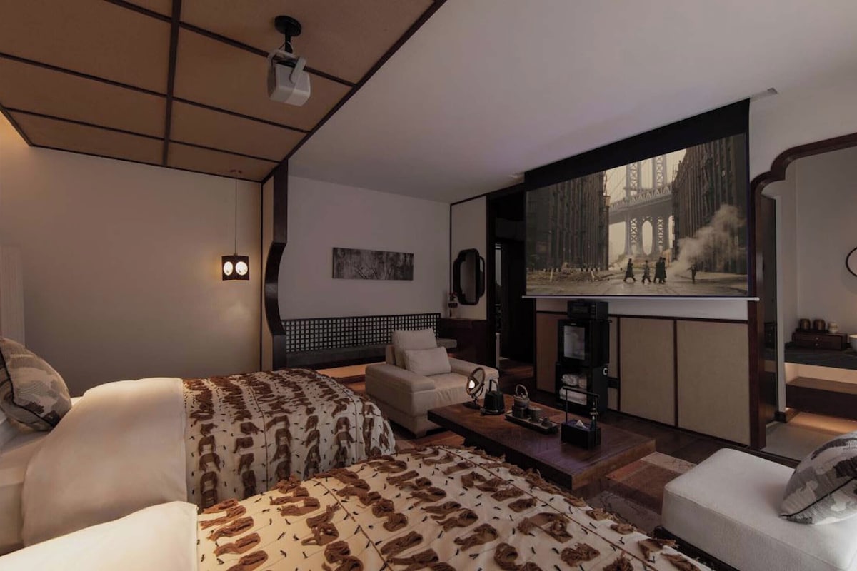 A modern hotel room with a large bed, a sofa, a coffee table, and a television.