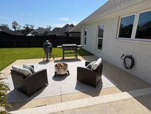 A backyard patio with outdoor furniture, a grill, and a barbecue.