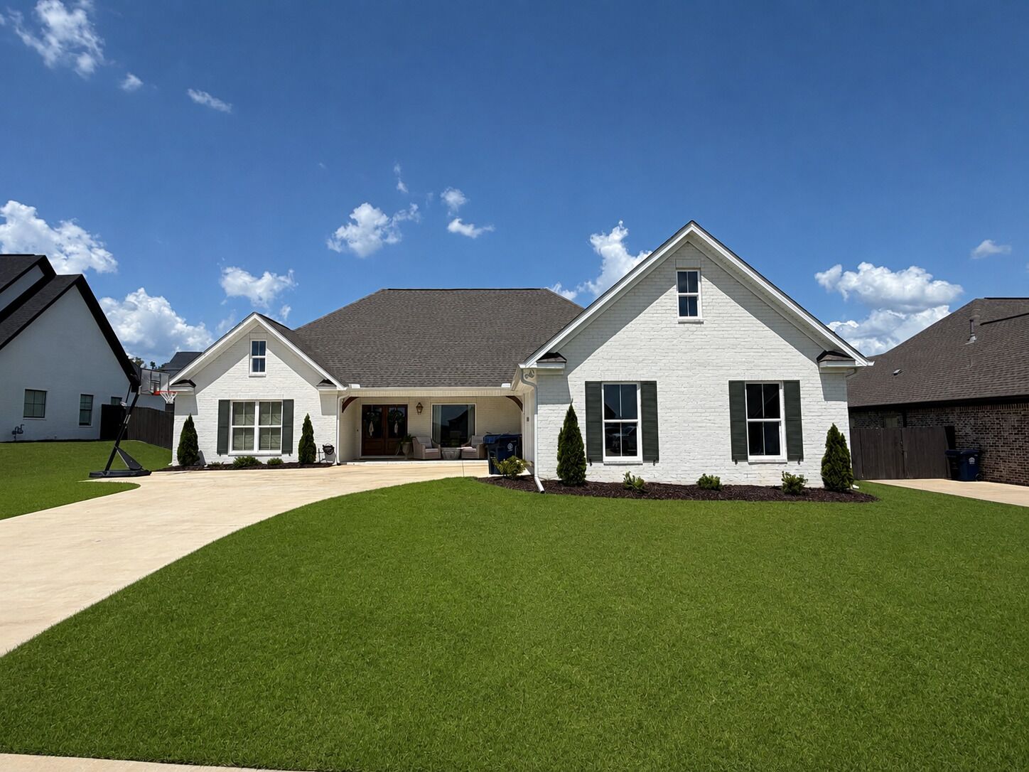 A two-story residential building with a front porch, a driveway, and a well-maintained lawn.