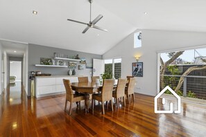 Eine geräumige Küche mit Essbereich, Holzboden und Deckenventilator.