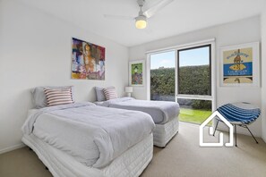 Ein Schlafzimmer mit zwei Betten, einem Deckenventilator und Blick ins Freie.