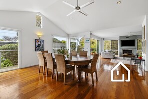 A spacious living area with a dining table, chairs, a sofa, and a fireplace. - Ocean Whispers *1 NIGHT FREE* Blairgowrie Back Beach Retreat (Blairgowrie)