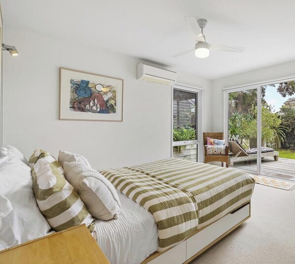 A bedroom with a bed, a ceiling fan, an air conditioning unit, a window, and a door leading to a balcony. - Ocean Whispers *1 NIGHT FREE* Blairgowrie Back Beach Retreat (Blairgowrie)