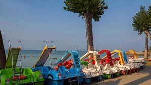 Een rij kleurrijke roeiboten op een zandstrand, met de zee op de achtergrond.