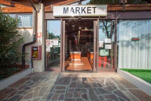 A market entrance with a sign, glass doors, and a stone-paved walkway. - Mobile home with air conditioning and parking (Sirmione)