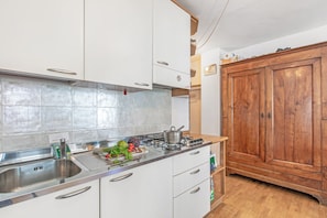 Eine Küche mit weißen Schränken, einer Edelstahl-Spüle und einem Holzschrank.