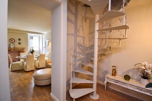 A modern interior with a spiral staircase, a dining area with a table set for four, and a small white console table with decorative items. - Luke Loft Lakeside Charm Central park, Salò, Italy (Salò)