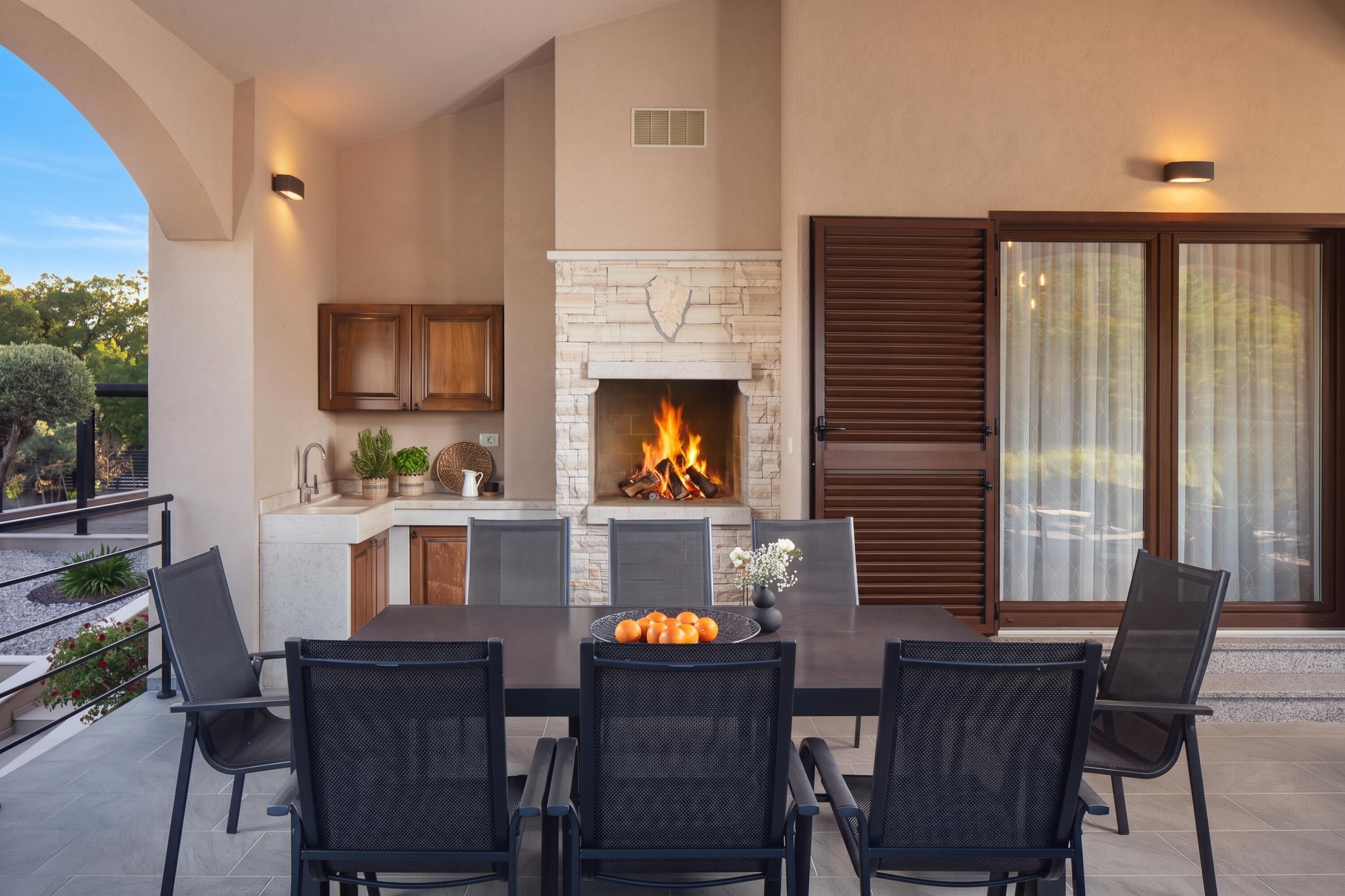 Une terrasse extérieure avec une cheminée en pierre, une table à manger et des chaises.