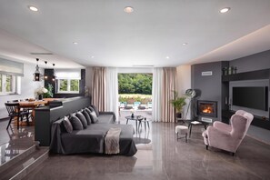 A modern living room with a sofa, a pink armchair, a fireplace, and a television. - Villa Terra with Pool & Sauna near Rabac, Labin, Croatia (Labin)
