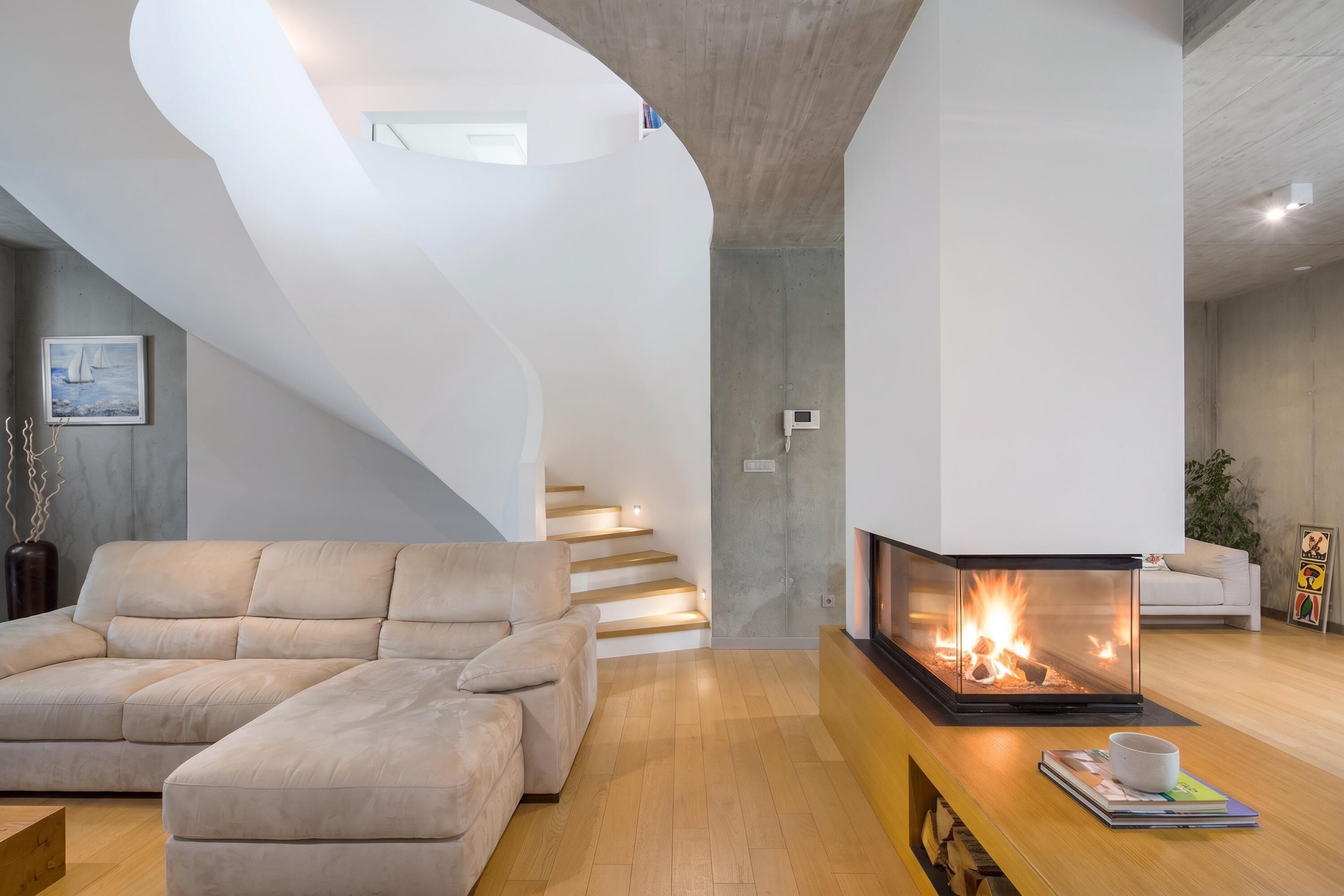 A modern living room with a sofa, a fireplace, and a staircase.