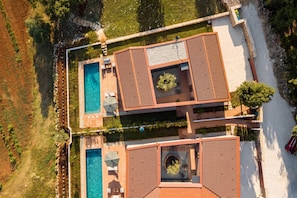 An aerial view of a resort with a swimming pool, sun loungers, and a landscaped garden.