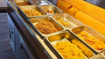 A buffet with various food items in metal trays.