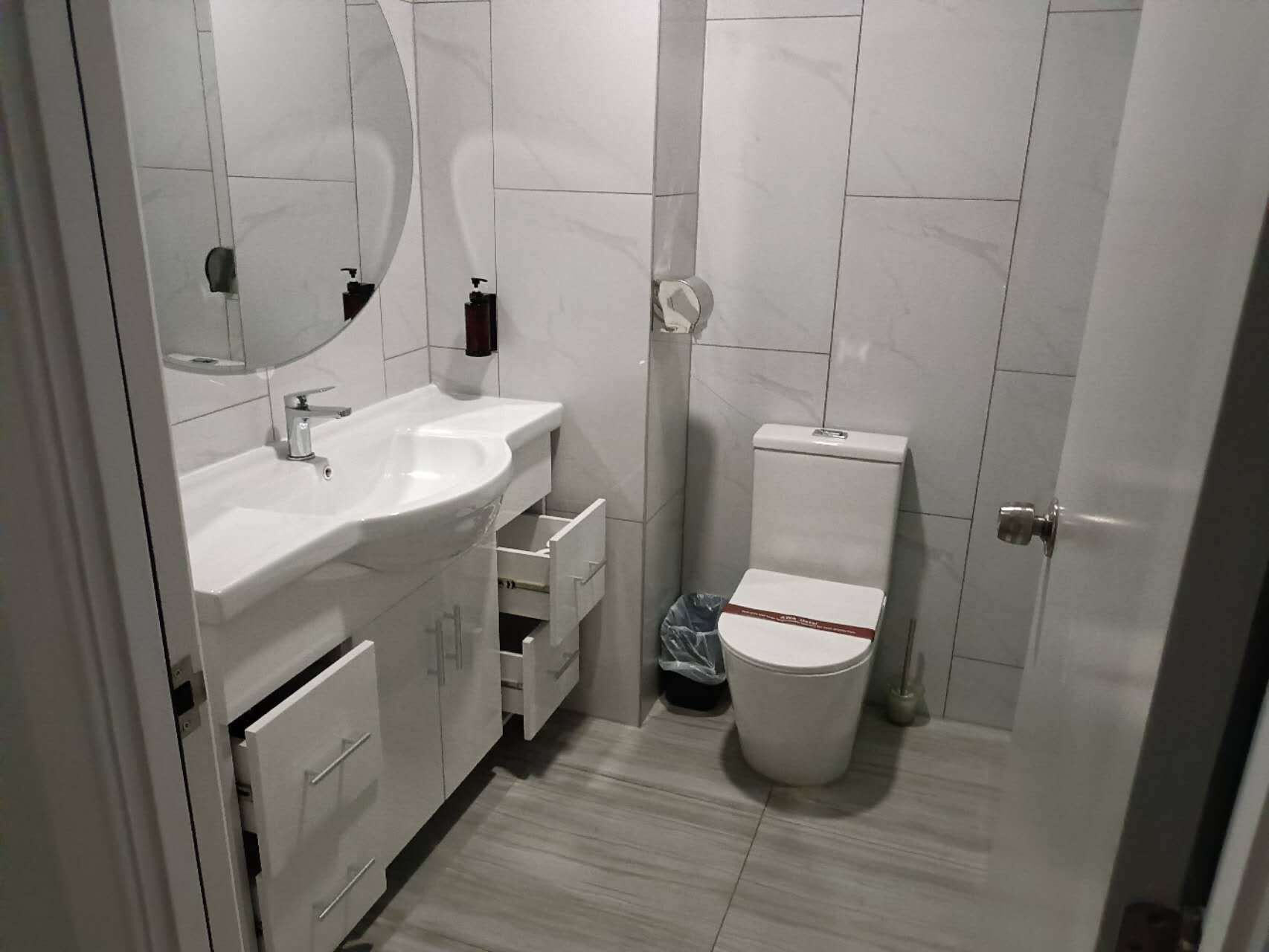 A modern bathroom with a white sink, mirror, and toilet.