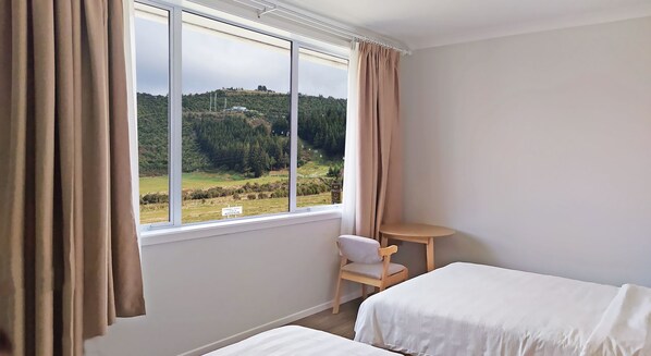 A bedroom with a large window, a chair, and a bed.