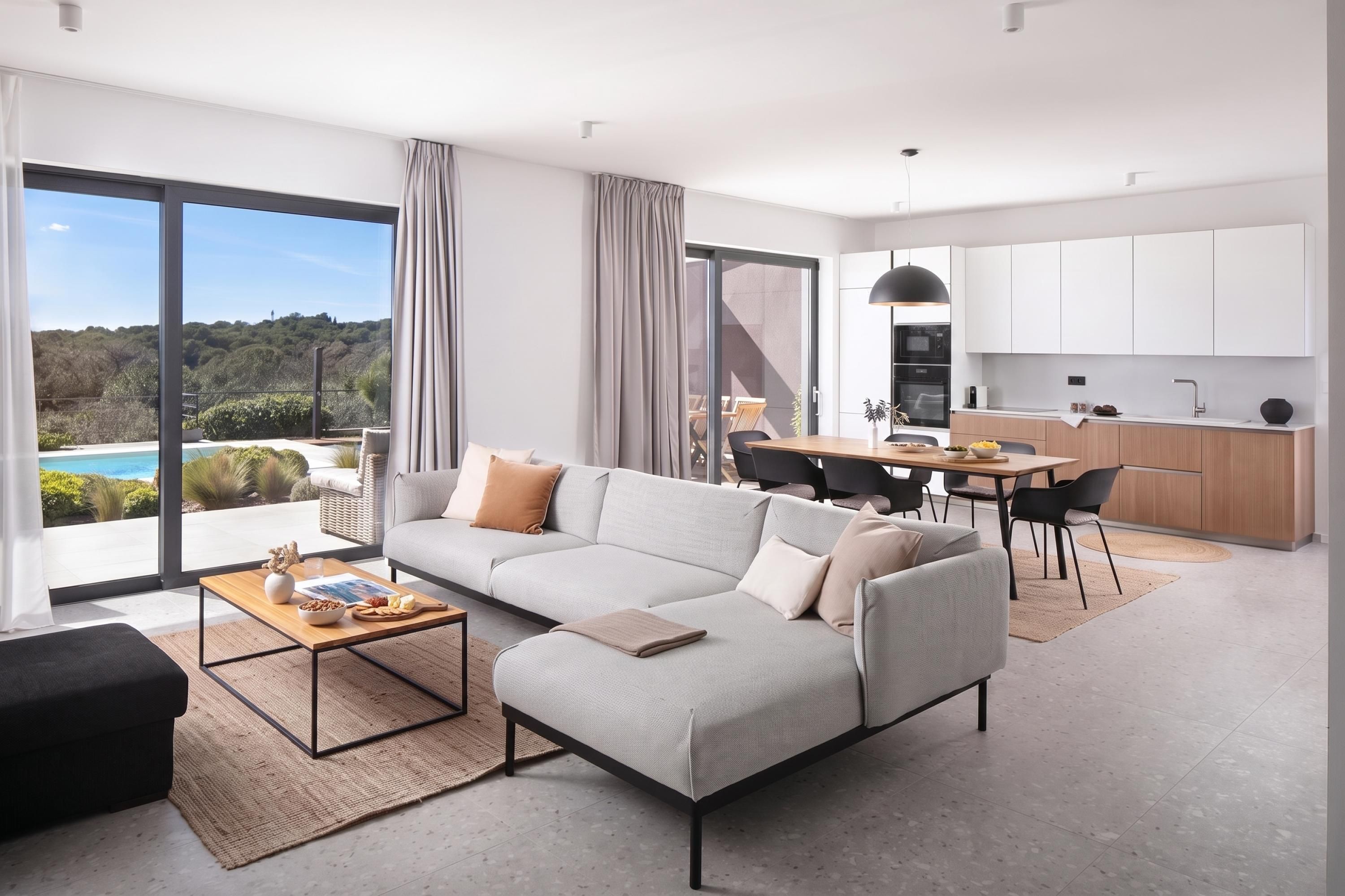A modern living room with a sectional sofa, a dining area, and a kitchen.