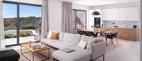 A modern living room with a sectional sofa, a dining area, and a kitchen.