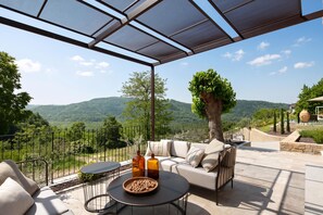 Un espace extérieur aménagé avec des sièges, offrant une vue sur les montagnes, doté d’une pergola et d’une piscine.