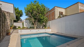 A rectangular swimming pool with a tiled deck surrounding it.