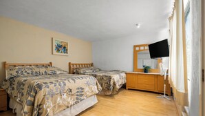 A bedroom with two beds, a dresser, a television, and a painting on the wall.