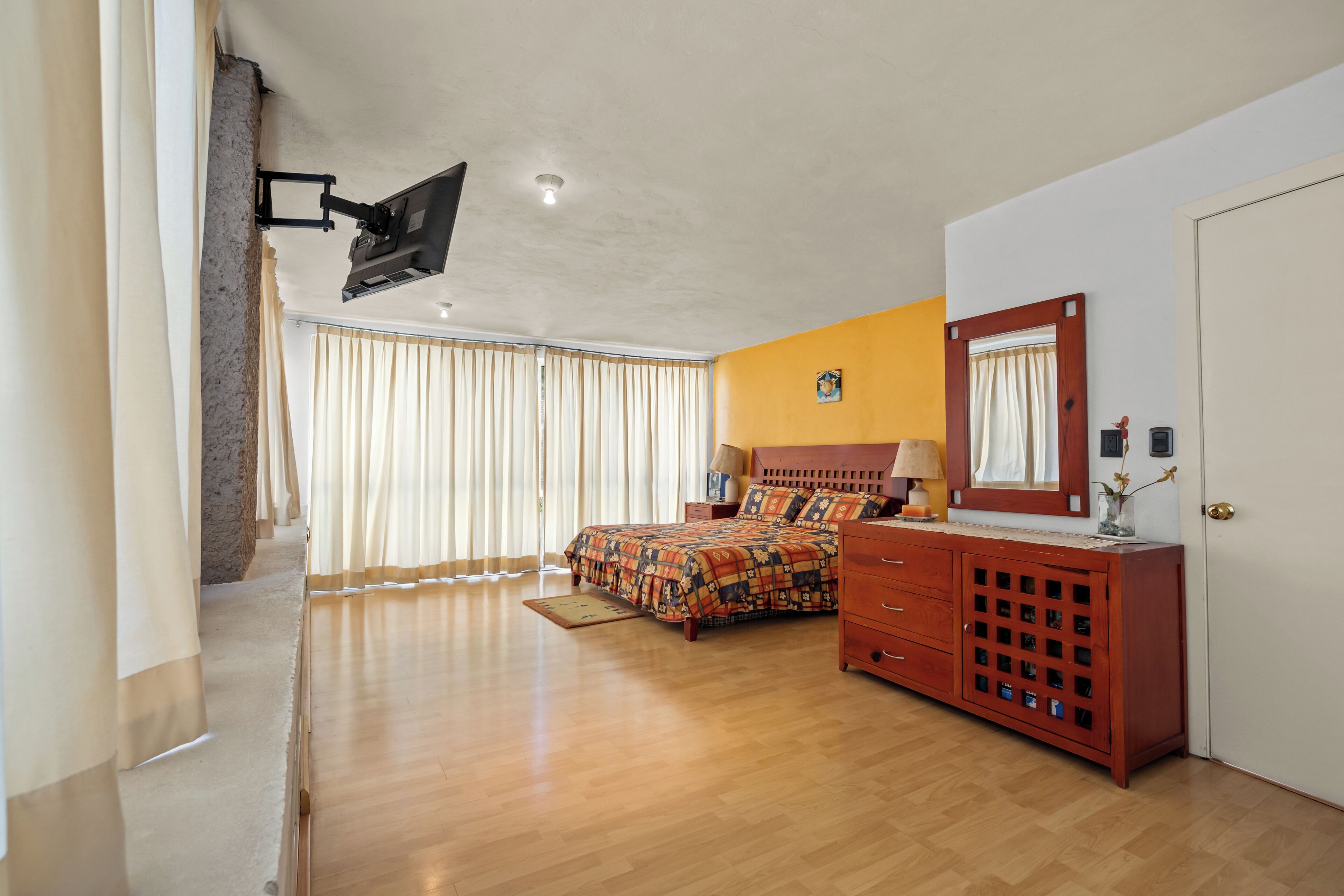 Ein Schlafzimmer mit einem Bett, einem Schminktisch, einem Spiegel und einem Deckenventilator.