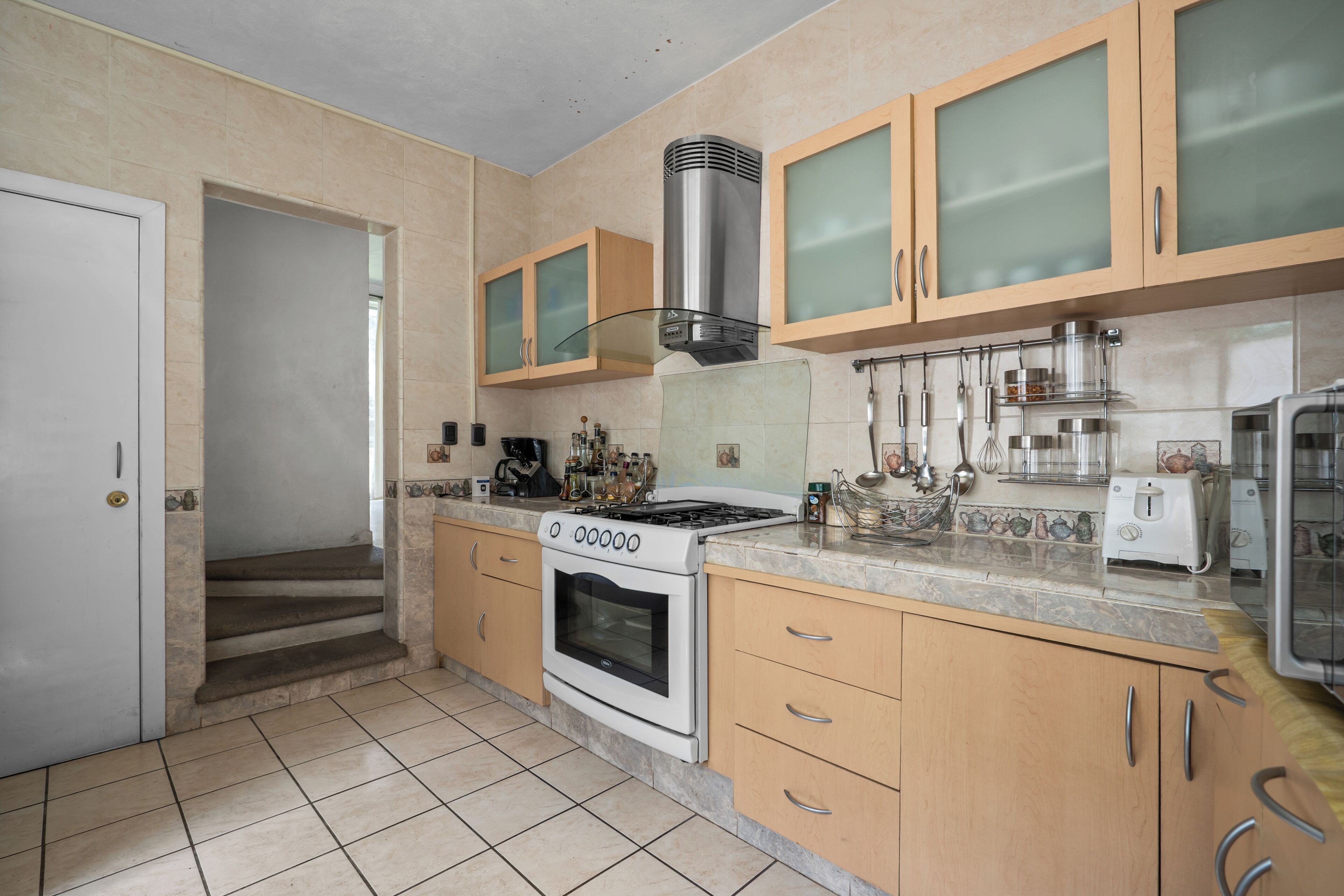 A kitchen with a stove, oven, and various utensils.
