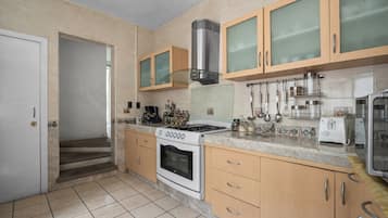 A kitchen with a stove, oven, and various utensils.