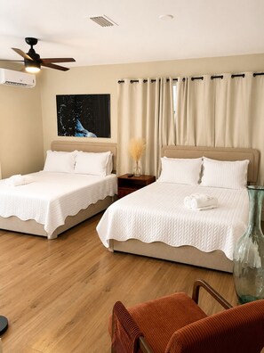 A hotel room with two beds, a ceiling fan, a night light, a painting, a vase, and a chair. - All New, Design District suite with free parking, centrally located. (Miami)