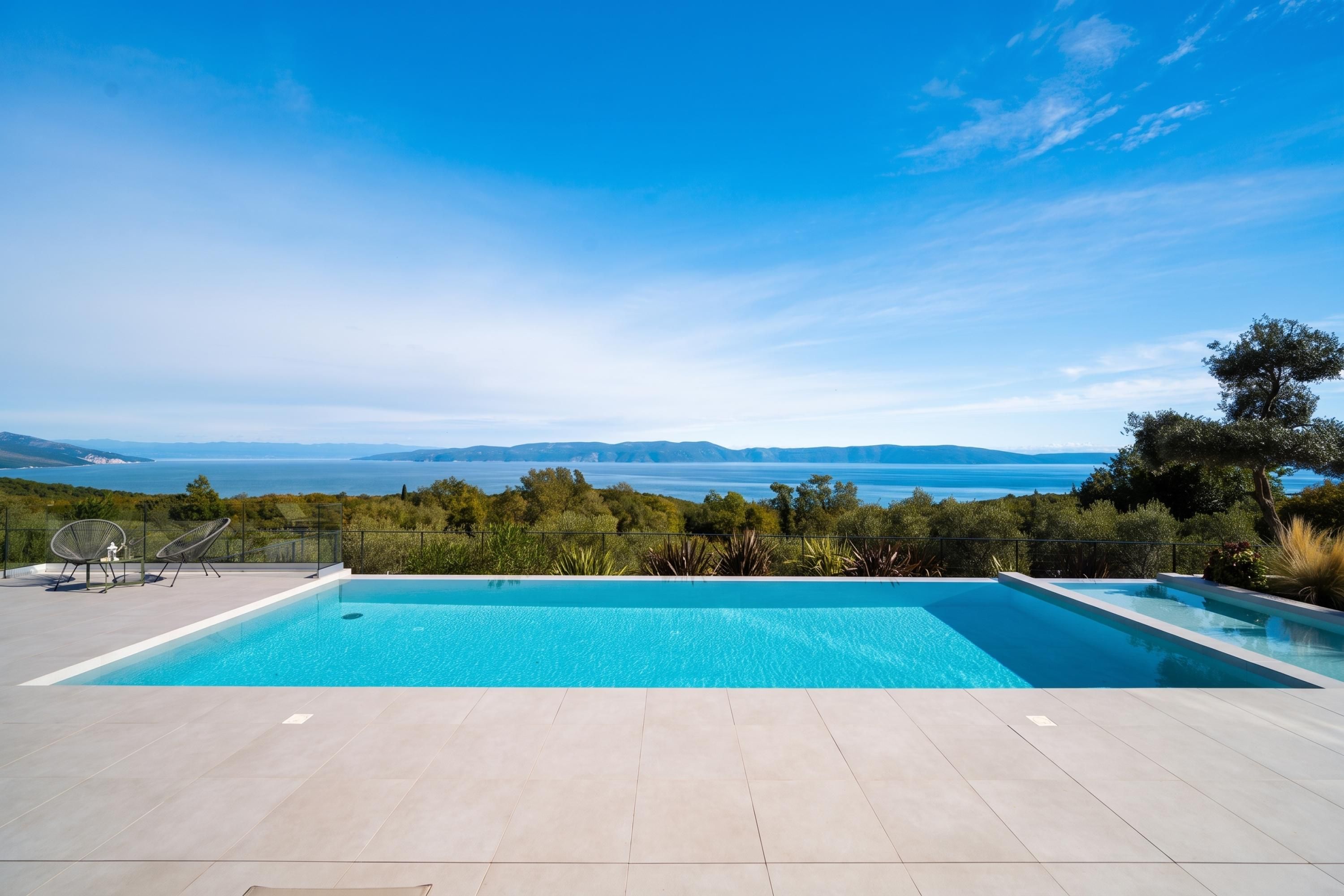 Une piscine avec vue sur la mer et les montagnes lointaines.