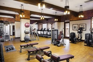 Een fitnessruimte met loopbanden, elliptische trainers, gewichtbanken en losse gewichten.