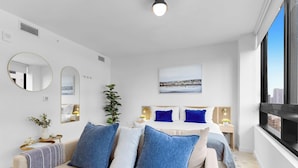 A modern bedroom with a bed, bedside tables, a mirror, a potted plant, and a cityscape view. - Miami Luxury Studio Rooftop Resort Style (Miami)