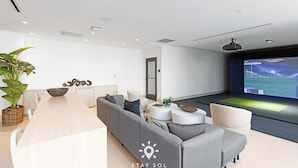 A modern living room with a sofa, coffee table, and a large screen displaying a game. - Miami Luxury Studio Rooftop Resort Style (Miami)