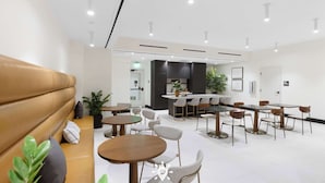 A modern hotel lobby with a seating area, tables, and a kitchen in the background. - Miami Luxury Studio Rooftop Resort Style (Miami)